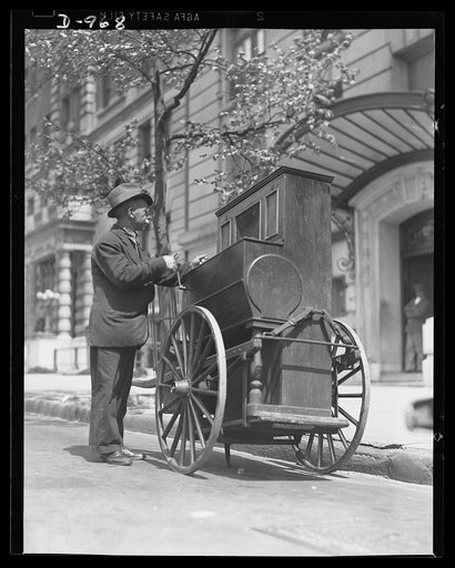 Urban America. An Italian organ grinder serenades the residents of a Riverside Drive, New York City apartment house with his barrel organ