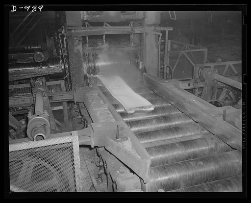 Steel alloy manufacture. Allegheny Ludlum Steel Corporation, Brackenridge, Pennsylvania. A white-hot ingot of steel is reduced to a slab on a two-high reversible type blooming mill. This slab will be converted further into either sheets or plates