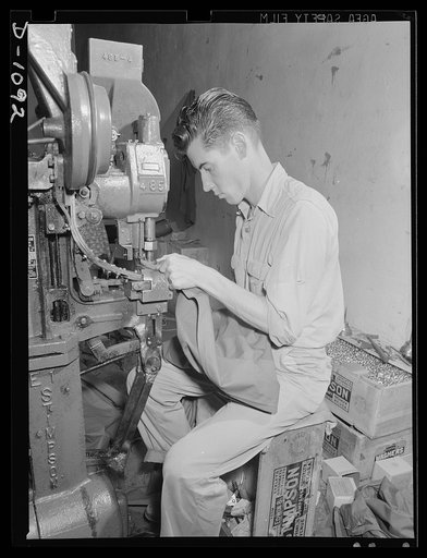 Langdon Tent and Awning Company, Wichita, Kansas. A modern automatic grommet-setting machine speeds the mass production effort of this plant which is turning out 1500 "pups" tents a day for the expanding defense Army
