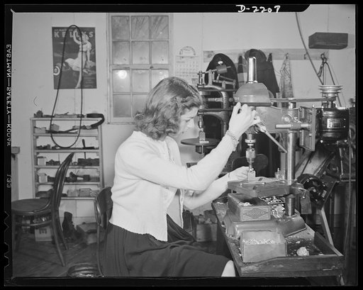 Dante Electric Company, Bantam, Connecticut. The shop is busy, so Anna, oldest of the five Dante girls lends a hand with a drill press. Anna operates the Bantam Beauty Salon, but because she has difficulty with hot water during the winter, she closes the shop from early January through March. Her "b