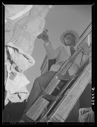 Rags. Collection and processing. Unloading bales of rags at a large Eastern processing plant. The bale is pulled onto the dolly by means of a hook. Shapiro Company, Maryland