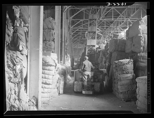 Rags. Collection and processing. Scene in the storeroom of a large Eastern rag processing plant. An electric crane lifts the bales and places them in piles, where they await sorting. Shapiro Company, Maryland