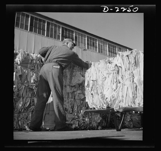 Rags. Collection and processing. Truckman unloading bales of waste paper outside a large Maryland plant which uses this scrap material in the manufacture of roofing felt and bases for linoleum floor coverings. Shapiro Company, Baltimore, Maryland