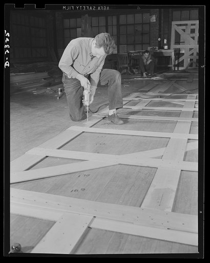 Shipbuilding. "Liberty" ships. Wooden templates are used as patterns for the laying out of a number of steel plates. This worker is carrying the templates for a gun foundation from the mold loft to the plate working section. All parts are prefabricated in this huge Eastern plant which formerly turne