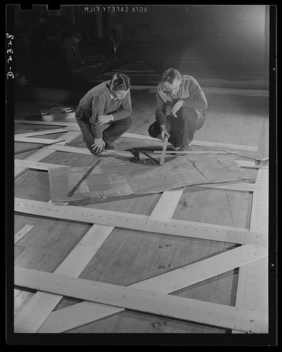 Shipbuilding. "Liberty" ships. Wooden templates are used as patterns for the laying out of a number of steel plates. This worker is carrying the template for a gun foundation from the mold loft to the plate working section. All parts are prefabricated in this huge Eastern plant which formerly turned