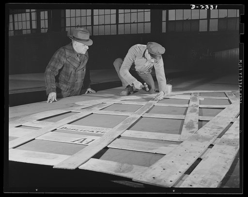 Shipbuilding. "Liberty" ships. This worker is laying out steel plates from wood templates, or patterns. The patterns indicate rivet hole locations and other necessary information. All parts are prefabricated in this Eastern plant which used to turn out freight cars. Completed sections are carried si