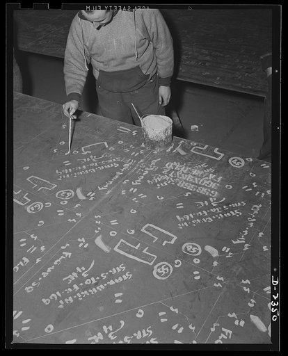 Shipbuilding. "Liberty" ships. This worker in the mold loft is painting over the marks made on steel plates from wooden templates, or patterns. The original marking is scratched onto the steel, and this man brings them out in white. All parts are prefabricated in this huge Eastern plant which former