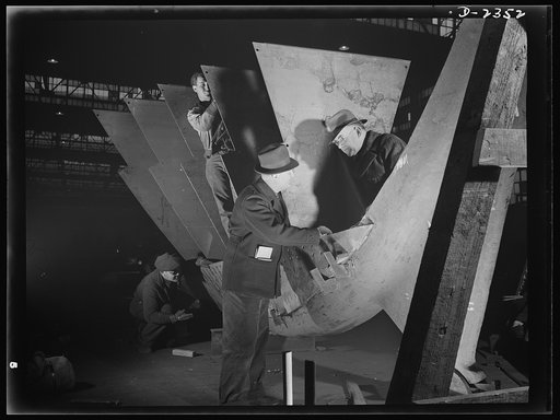 Shipbuilding. "Liberty" ships. The maritime inspector at a large Eastern shipyard is checking over, with the foreman, the stem assembly for a new member of the "Liberty Fleet." All parts are prefabricated in this huge Eastern plant which formerly turned out freight cars. The completed sections are t