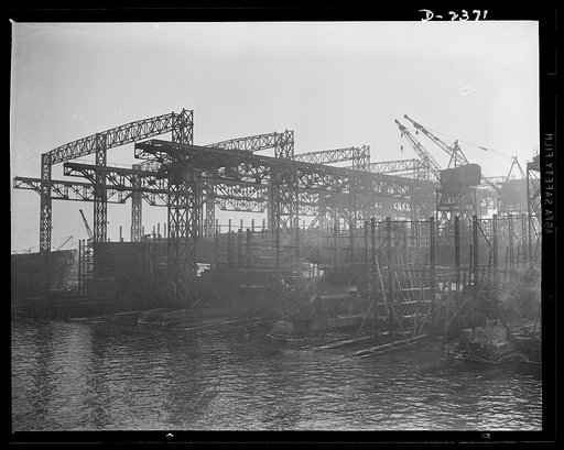 Shipbuilding. "Liberty" ships. A view from the water of the shipways at a large Eastern yard. At the left is seen the old-style superstructure, with tracks for two-way overhead cranes, while at the right, running on ground tracks, are the more modern cranes, designed for hoisting from any angle. Bet