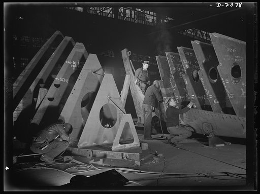 Shipbuilding. "Liberty" ships. In an abandoned freight car factory near the Atlantic coast, sections of sleek freighters for the merchant fleet are being prefabricated. Present rate of production is one a week. The men shown at work here believe they can increase that rate to one in six days