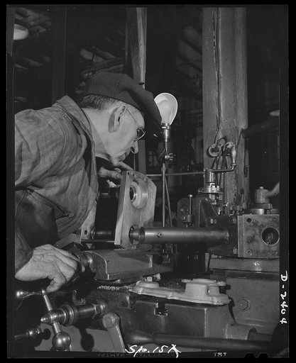 Conversion. Merry-go-round plant. The capable hands of this craftsman belie the adage that an old dog cannot learn new tricks. For years those hands have carved most of the horses that appear on American carrousels. For the duration they're operating this lathe and machining landing gear housings fo
