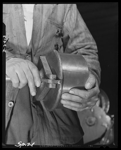 Conversion. Merry-go-round plant. These hands used to turn out merry-go-rounds to gladden the hearts of the nation's children. The carrousel plant in which they work is now engaged in producing war parts on subcontracts from army and navy contractors. Above is a completed shell ejector getting its f
