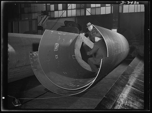 Shipbuilding. "Liberty" ships. These are rolled plates for the shaft tunnel of one of Uncle Sam's new "Liberty Ships," under construction at a large Eastern shipyard. All parts are prefabricated in this large Eastern plant which formerly turned out freight cars. The completed sections are then carri