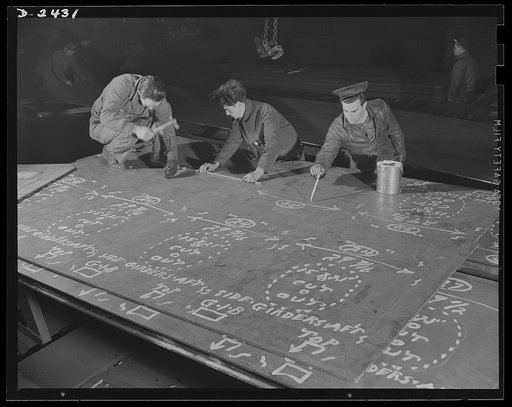 Shipbuilding. "Liberty" ships. This worker in the mold loft is painting over the marks made on steel plates from wooden templates, or patterns. The original marking is scratched onto the steel, and this man brings them out in white. All parts are prefabricated in this huge Eastern plant which turned