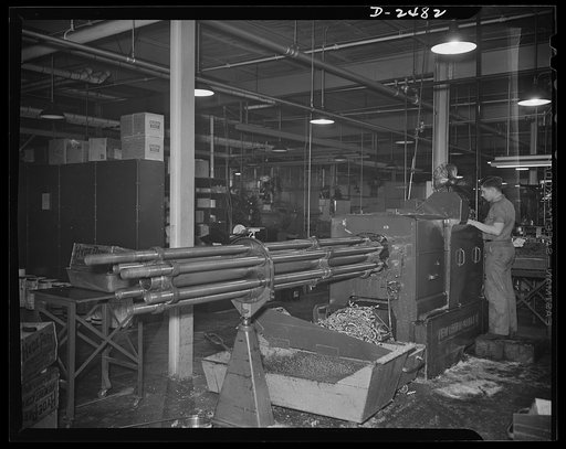A New Britain-Gridley lathe is worked by an experienced operator at a Midwestern company. The machine which formerly made spur gears, worm wheels and commentator rings has been converted to war use by being tooled with an eccentric spindle and thread rolling attachment for the production of twenty-m