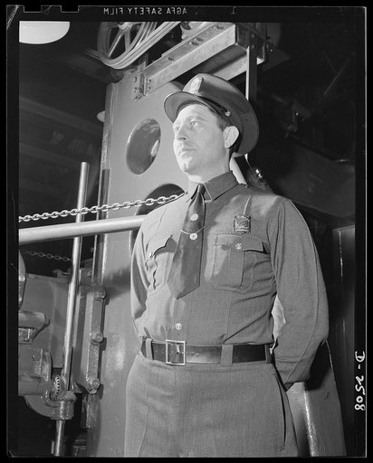 Conversion. Automobile industry. No person or machine is permitted in any of America's war production factories without thorough inspection by plant patrolmen. Here a guard watches installation of a machine newly converted from automobile production to production of airplane parts. The Plymouth Comp