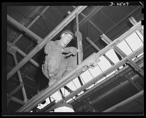 Conversion. Automobile industry. To convert automobile assembly plants into war production plants, much of the old machinery must be removed. This workman, perched high, is helping to speed the changeover by removing an overhead conveyor. The Plymouth Company, Chrysler Corporation, Detroit, Michigan