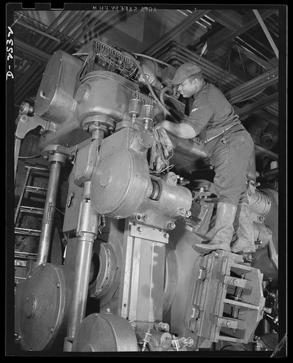 Conversion. Automobile industry. Preparing a huge automobile production machine for temporary storage, maintenance man cleans up the machine prior to conversion to war production. The Plymouth Company, Chrylser Corporation, Detroit, Michigan
