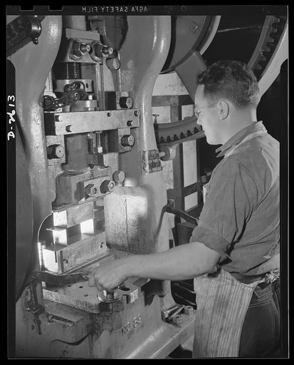 Conversion. Toy factory. Skillfully operating this massive press, a worker stamps out part of a filter box essential to the armed forces. Before conversion of this machine, metal toys were stamped out. The changeover consisted chiefly of new dies. Keystone