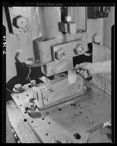 Conversion. Toy factory. Between the heavy punch and the die, a vital war product is being turned out by a press which once produced only metal toys and movie projectors. U-shaped object is part of radio filter box essential to the army. Keystone