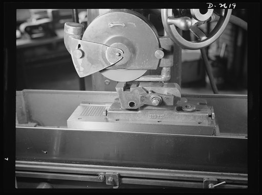 Conversion. Safety razor plant. Closeup of grinder converted from production of safety razors to tool-posts. Only conversion necessary in this instance is of the tool holding the V-block, which is held in place by the magnetic chuck. Gillette
