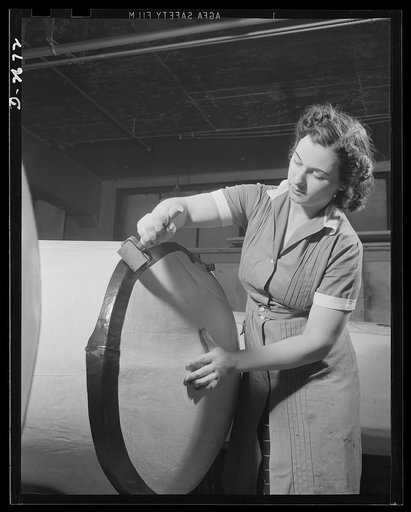 Self-sealing fuel tanks. The heavy paper building forms for bullet-sealing fuel tanks must be covered with cloth. Women are doing a large portion of the work in turning out these tanks. This girl is applying a sealing strip to the edges of the building form to keep the cloth taut. Goodrich