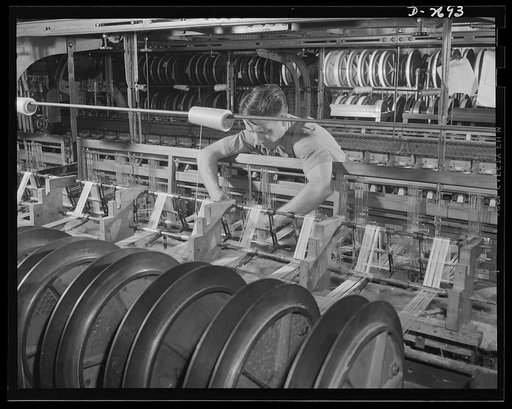 Fiberglass manufacture, Owens-Corning, Toledo, Ohio. All-glass yarns in this photographs are being woven on standard textile machinery into tape that subsequently will be used to insulate electrical equipment. Inorganic fiberglass electrical insulation makes possible the building of electrical equip