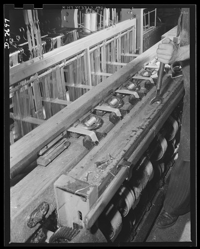 Fiberglass manufacture, Owens-Corning, Toledo, Ohio. Miles and miles of all-glass tape are woven on looms like this one in New England and the South, as well as in plants of Owen-Corning Fiberglass Corporation, to meet urgent war production demands for fiberglass electrical insulation