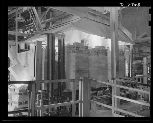 Fiberglass manufacture, Owens-Corning, Toledo, Ohio. Intense heat is needed to melt the inorganic ingredients of the batch from which fiberglass insulating wool is manufactured. Twenty-four hours a day, seven days a week, this gas-fired furnace maintains the temperatures required in the process