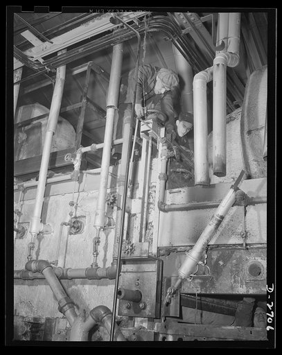 Fiberglass manufacture, Owens-Corning, Toledo, Ohio. Workmen in a plant of the Owens-Corning Fiberglass Corporation are installing the gas-firing lines on a newly-built furnace to expand manufacturing capacity for thermal and acoustical insulation needed in the battle for production