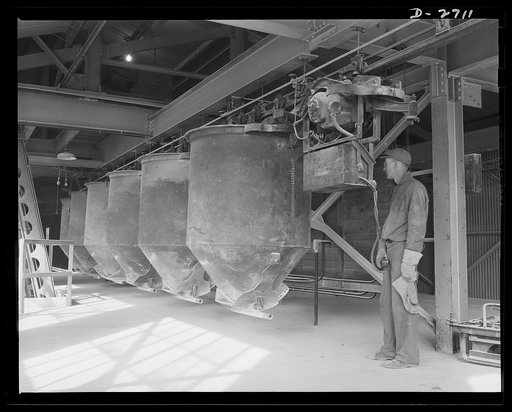 Fiberglass manufacture, Owens-Corning, Toledo, Ohio. Along an overhead monorail system, cans containing the carefully compounded ingredients of the batch, move to the huge furnaces for conversion into molten glass from which fiberglass materials are manufactured in a plant of Owens-Corning Fiberglas