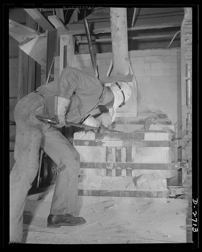 Fiberglass manufacture, Owens-Corning, Toledo, Ohio. Feeding the batch into what glass men call "the doghouse"--the charging end of a furnace--this worker is servicing one of the tanks used to manufacture fiberglass thermal and acoustical insulation in a plant of Owens-Corning Fiberglass Corporation