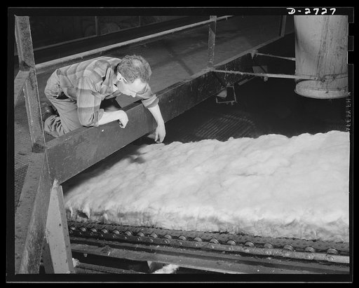 Fiberglass manufacture, Owens-Corning, Toledo, Ohio. In a resilient, lightweight blanket of interlaced fibers, fiberglass thermal insulation is carried along from the furnaces where it is produced to be packaged or further fabricated into the forms required by Army and Navy specifications