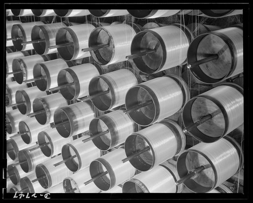 Fiberglass manufacture, Owens-Corning, Toledo, Ohio. Millions of miles of glass filament are drawn from the forming tubes and twisted into yarns which will be braided over flameproof electrical wire essential to the construction of modern bombers. Each strand coming from each tube contains over 200 