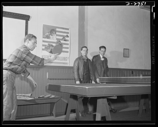 Fiberglass manufacture, Owens-Corning, Toledo, Ohio. Fiberglass workers in a plant of the Owens-Corning Fiberglass Corporation relax during the lunch hour. An OEM (Office of Emergency Management) poster on the wall reminds them to "Keep 'em rolling" for the all-out war effort