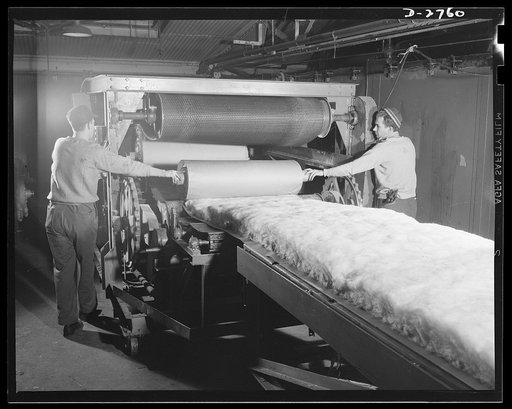 Fiberglass manufacture, Owens-Corning, Toledo, Ohio. As the blanket of fiberglass thermal insulation moves along on a conveyer, it is packaged in rolls. These rolls then are taken elsewhere in the plant to be fabricated into pipe covering or insulating blocks