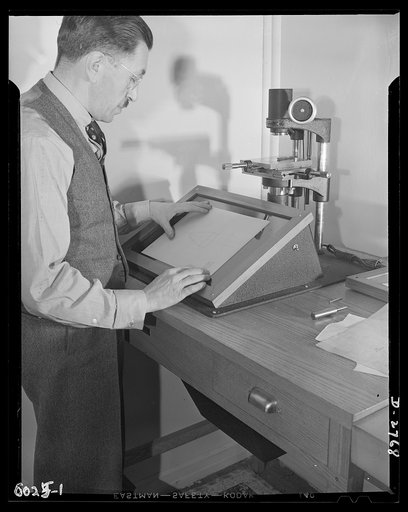 Conversion. Soft drink dispenser plant. The president of an Eastern manufacturing company now producing war essentials on prime and subcontracts, checks a contour gauge manufactured for Army arsenals. Gauges for measuring cartridges and other war materials must be accurate to the 2/10,000 of an inch