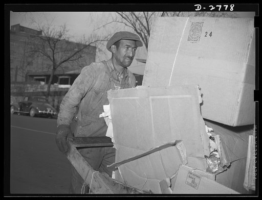 Scrap collection. Junk man pushing his cart loaded with a day's pickings on his way to sell the paper, cardboard and rags to a large scrap dealer. Shapiro Company, Baltimore, Maryland