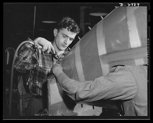 Conversion. Auto body plant. Workers inserting screws in the tail section of one of Uncle Sam's airplanes. Note the "headless" man at right. He's holding a light inside the section to facilitate the work. Briggs Manufacturing Company, Detroit, Michigan
