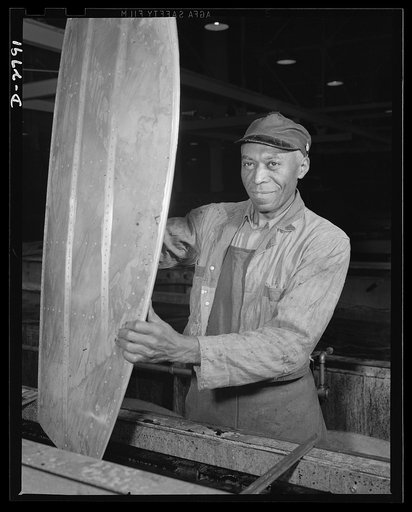 Conversion. Auto body plant. This Negro worker is dipping the tail section of an airplane in bath, a necessary process prior to painting. Location: a large Midwest factory, recently converted from manufacture of automobile bodies to essential war production. Briggs Manufacturing Company, Detroit, Mi