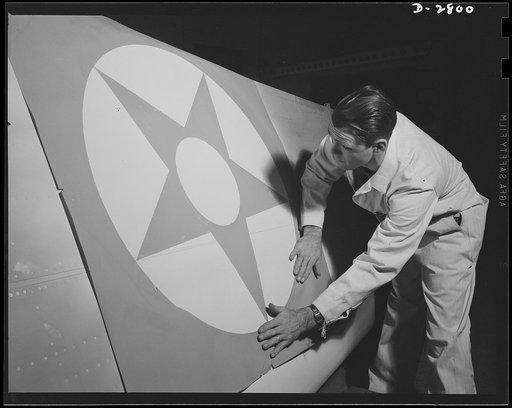 Conversion. Auto body plant. He's marking this wing with the colors of victory--red, white and blue. Stencil being applied to wing tip in one of America's automobile body plants newly converted to airplane Production. Briggs Manufacturing Company, Detroit, Michigan