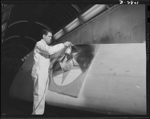Conversion. Auto body plant. He's marking this wing with the colors of victory--red, white and blue. Stencil being applied to wing tip in one of America's automobile body plants newly converted to airplane Production. Briggs Manufacturing Company, Detroit, Michigan