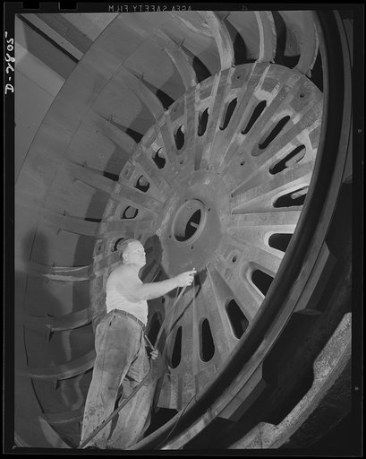 Giant tire manufacturer. This husky workman, standing six feet four inches tall, looks small indeed as he uses air pressure to clean the lid of the world's largest vulcanizing unit in an Eastern tire plant. The top section of this mold being prepared to vulcanize a large bullet-sealing gasoline tank
