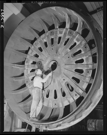 Giant tire manufacturer. This husky workman, standing six feet four inches tall, looks small indeed as he uses air pressure to clean the lid of the world's largest vulcanizing unit at a large Eastern tire plant. The top section of this mold, now being prepared to vulcanize a large bullet-sealing gas