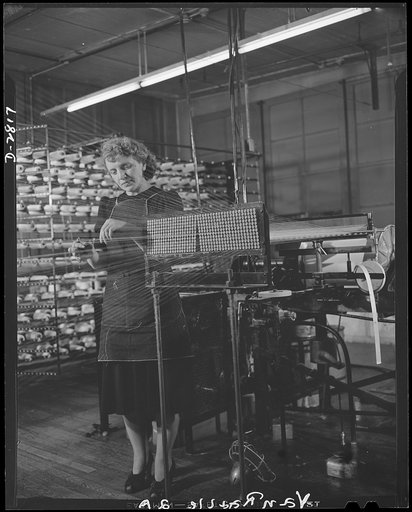 Conversion. Hosiery factory. She wears them but she doesn't make them any more. Conversion of a large Eastern mill from production of women's stockings to mosquito netting for the Army and Navy, gives this worker a vital defense job. She's drawing yarn from warp machine into warp beams prior to its 