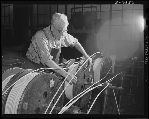 Transformer manufacture. Forty years with a great Eastern electric company, George Matheson, expert electrical worker, skillfully adjusts spools of copper wire feeding on to the large 120 turn coils which he turns. Production of all such electrical equipment has been greatly stepped up due to the wa
