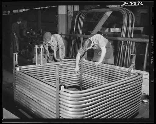 Transformer manufacture. When completed, this transformer will supply electric furnaces with the power needed to produce steel for Uncle Sam's ships and tanks and guns. The cooling coils pictured here are made of copper. A new process of forced oil cooling adds efficiency to these coilings; oil thro