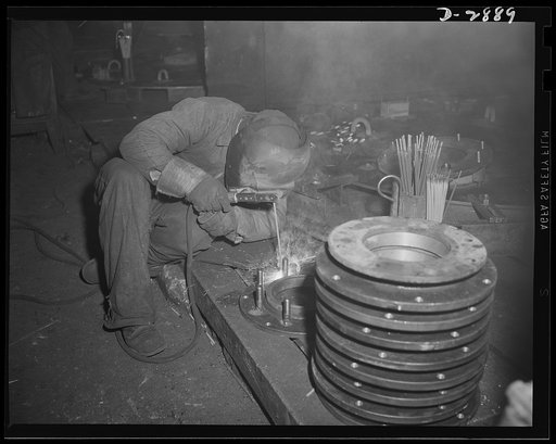 Transformer manufacture. Welding is an intrinsic part of the manufacture of transformers. This welder is employed by a large Eastern electrical company whose power transformers are needed by many factories engaged in war production. He's welding cover flanges for steel transformer tanks. Westinghous