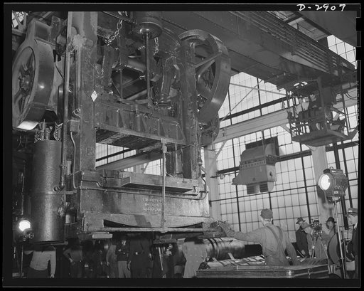 Conversion. Automobile plant. A giant overhead crane moves a 6D Bliss press, weighing seventeen tons, from a plant being entirely cleared for outright conversion to armament Production. When set up in another of the buildings of a big automobile factory, this press will form door trim panels of 4 x 