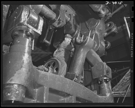Conversion. Automobile plant. Preparing to swing back and clear the long toggle arm of a huge 90T96 Cleveland press so the large connecting rod can be brought in place under the crankshaft. The 120-ton machine will perform a major operation on hood panels for 4 x 4 army trucks. It was moved piece by
